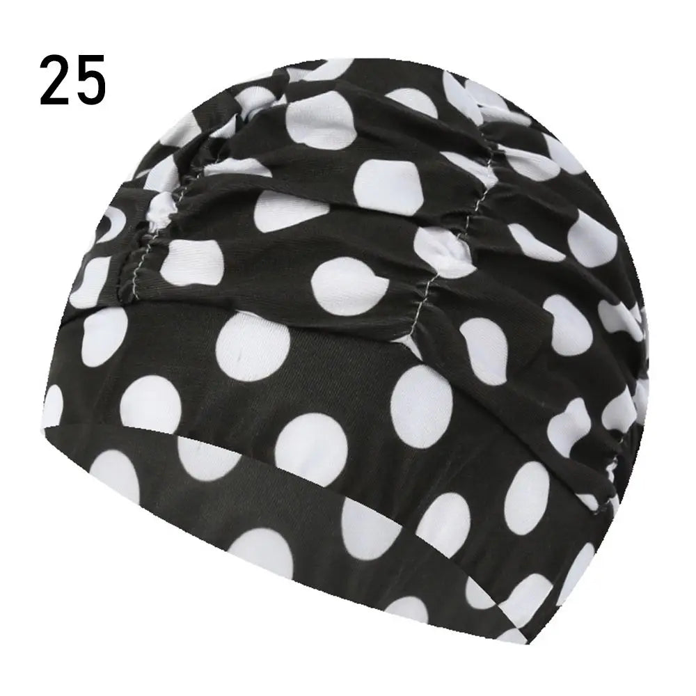 Black and white polka dot elastic nylon turban swimming cap shown from the side.