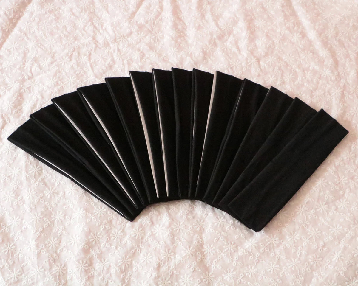 A fan of black elastic headbands arranged in a semi-circle on a white surface.
