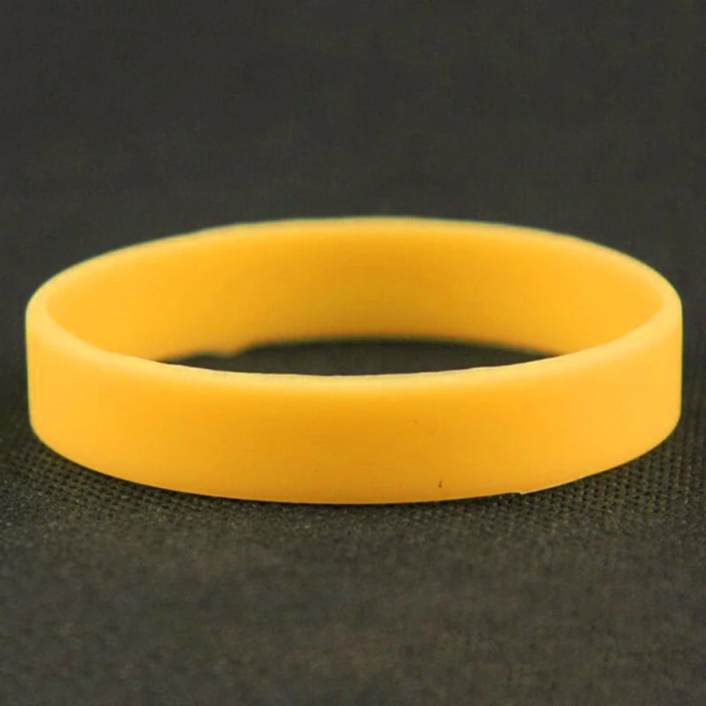 A yellow silicone elastic wristband lying on a dark surface.