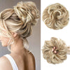 A woman shows off a blonde, messy curly hair bun hairstyle with extensions.