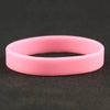 A pink silicone elastic wristband lying on a dark surface.