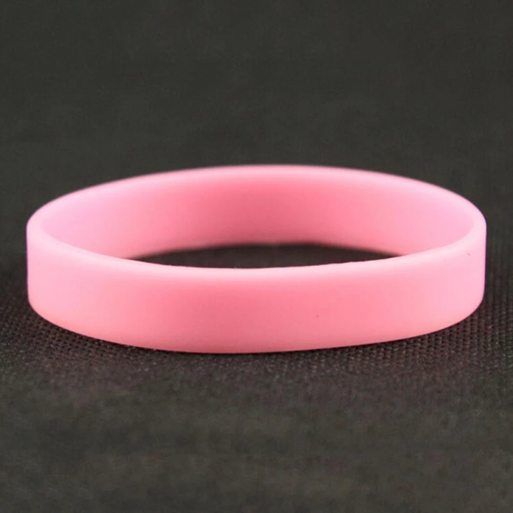 A pink silicone elastic wristband lying on a dark surface.