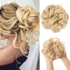 Blonde hair extensions styled in a messy curly bun with loose waves.