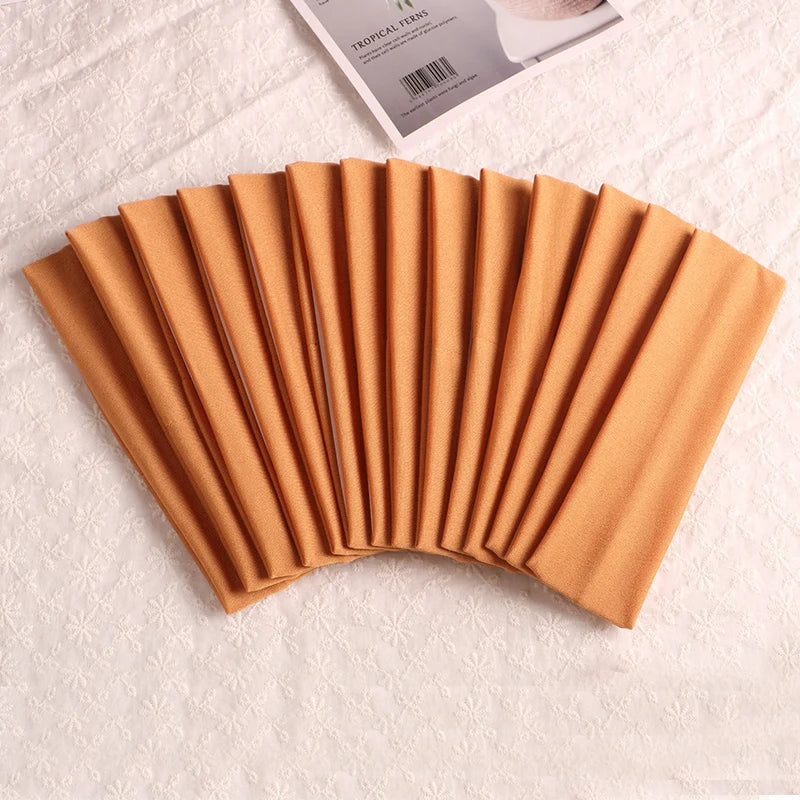 A fan of multi-use elastic headbands for sports and hair in a warm tan color.