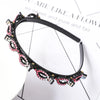 A black headband decorated with pink and clear rhinestones and pearls.