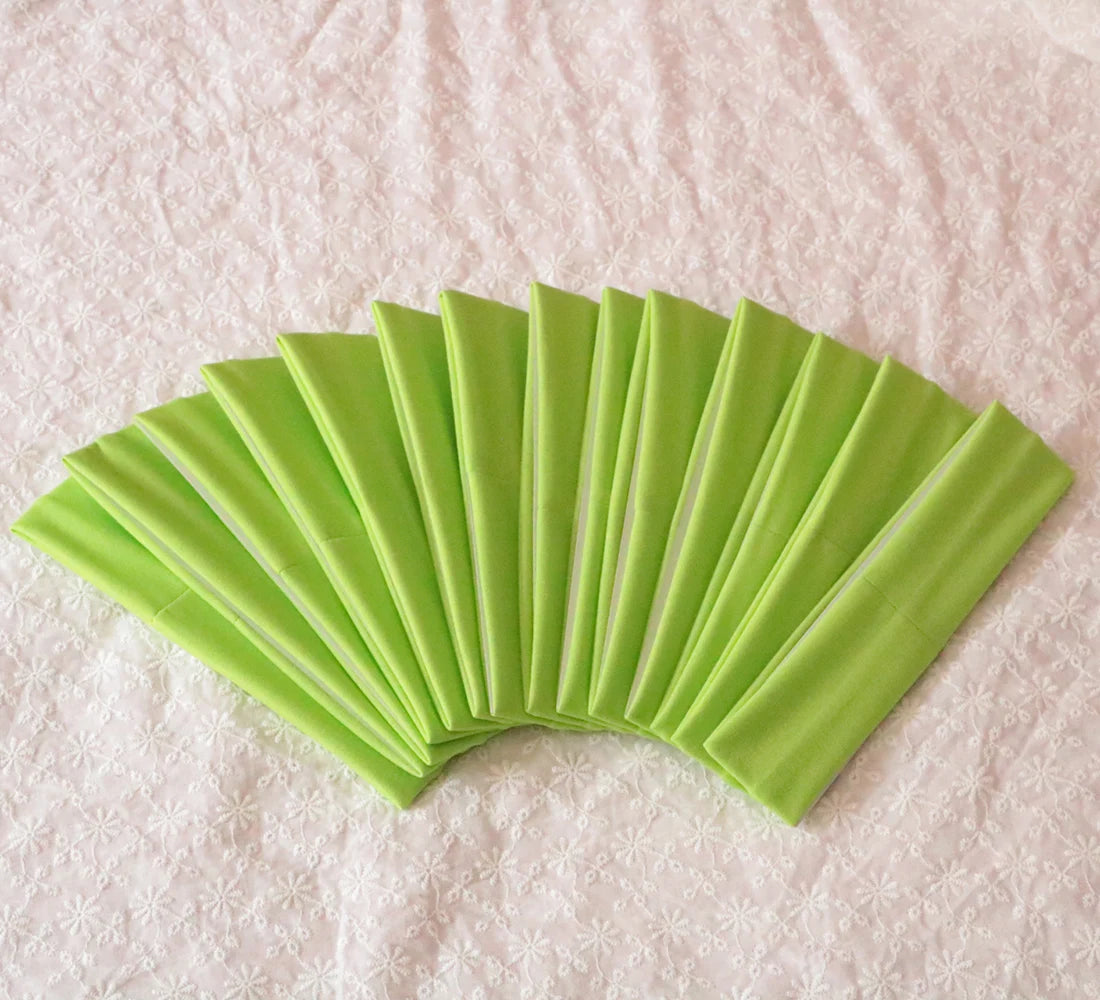 A fan of bright lime green elastic headbands arranged in a curved, overlapping fan shape on a white surface.