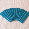 A fan of teal elastic headbands arranged in a semi-circle on a pink textured surface.