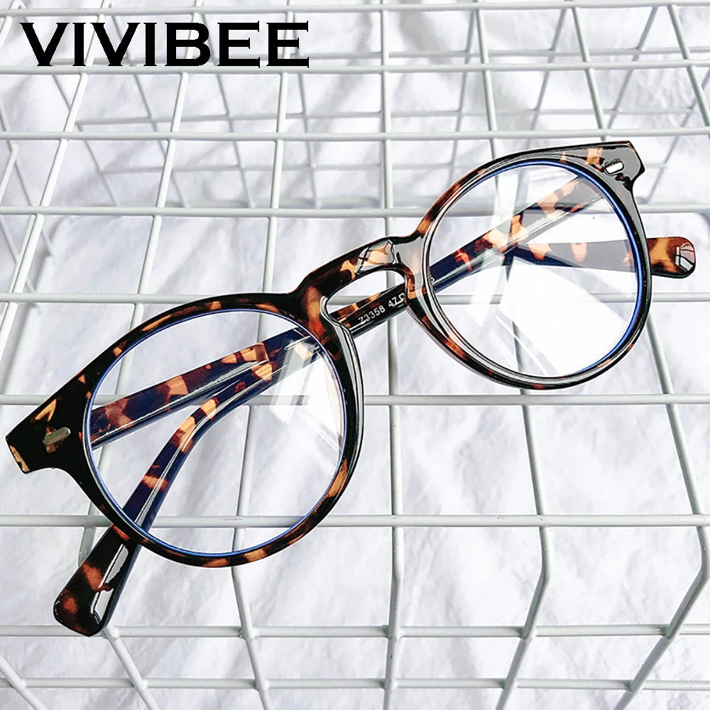 A pair of brown and blue patterned square frame glasses resting on a white wire mesh background.