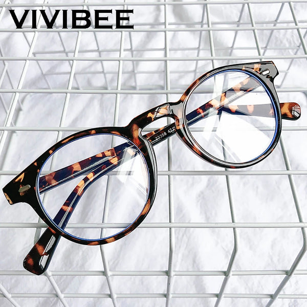 Une paire de lunettes à monture carrée à motifs marron et bleu, posées sur un fond de grillage blanc.