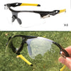 A pair of black and yellow sport sunglasses shown in a close-up against a green outdoor background.