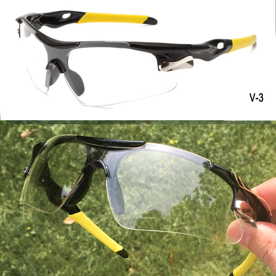 A pair of black and yellow sport sunglasses shown in a close-up against a green outdoor background.