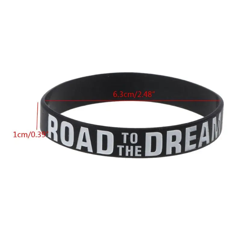 Black silicone elastic bracelet with the text Road to the Dream engraved on it.