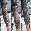 A close-up of a person wearing dark gray reusable UV protection tattoo arm sleeves featuring intricate black and orange triba