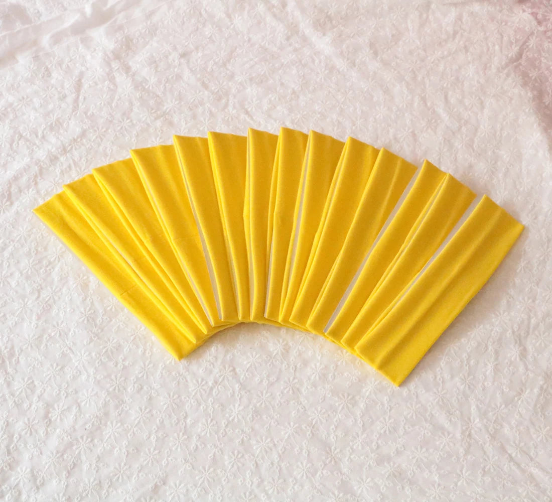 A fan of bright yellow elastic headbands arranged in a semi-circle on a white surface.