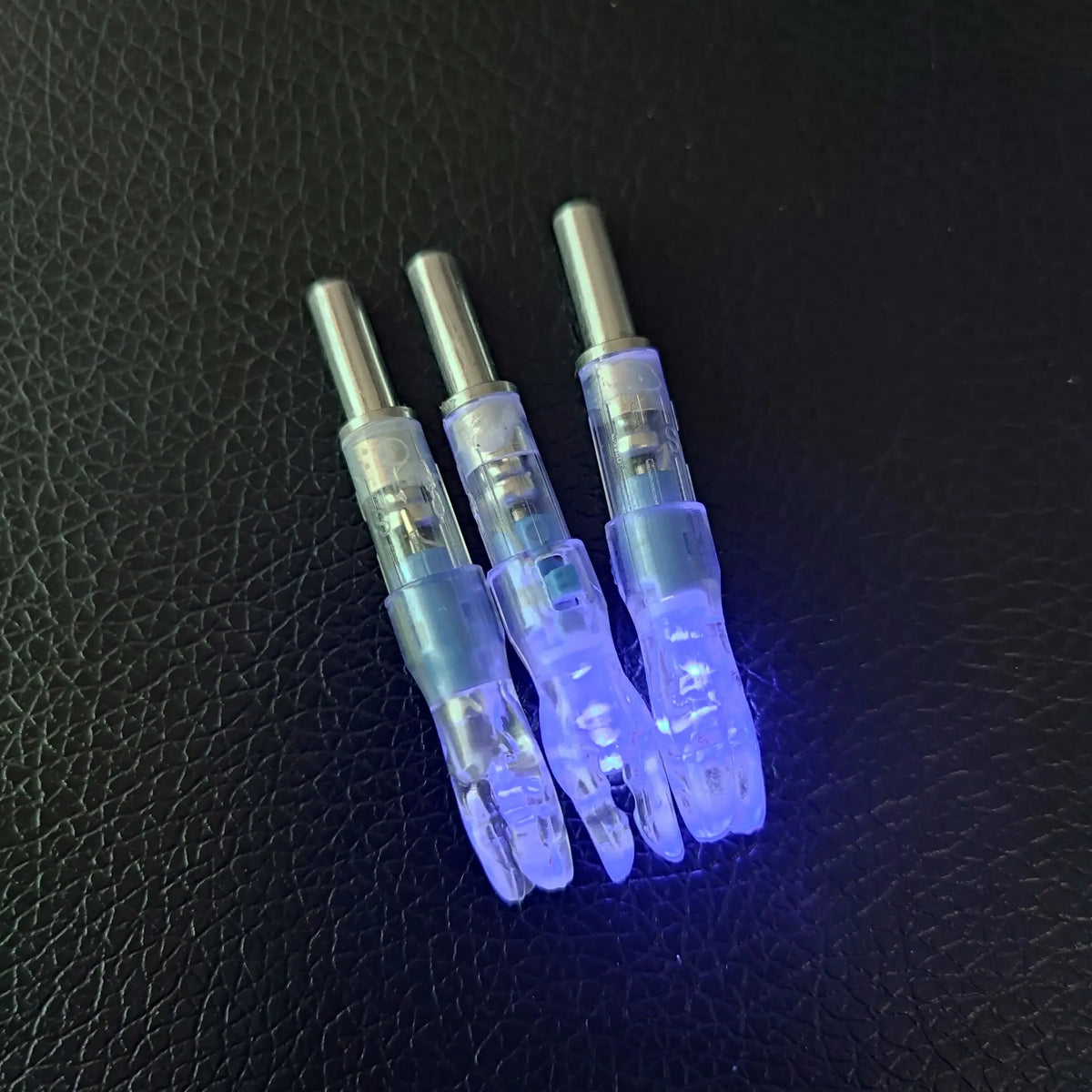 Three lighted arrow nocks for archery displayed against a dark background.