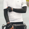 A man wearing a white cycling jersey and black arm sleeves is holding a bicycle handlebar.
