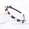 Black headband adorned with multiple round pearl and rhinestone embellishments