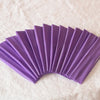 A fan of purple elastic headbands arranged in a semi-circle on a white textured surface.