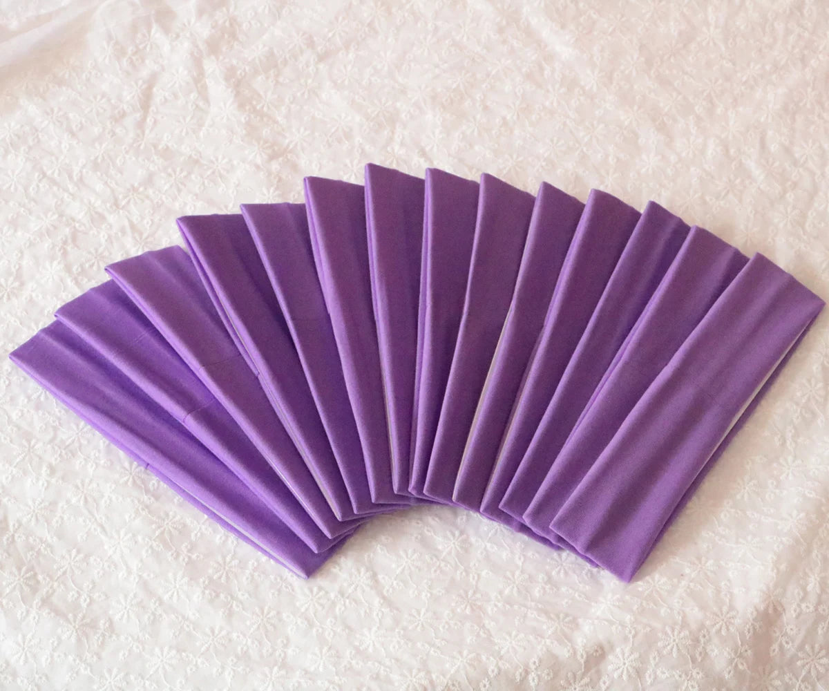 A fan of purple elastic headbands arranged in a semi-circle on a white textured surface.