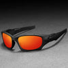 A pair of black sports sunglasses with bright orange lenses resting on a gray surface.