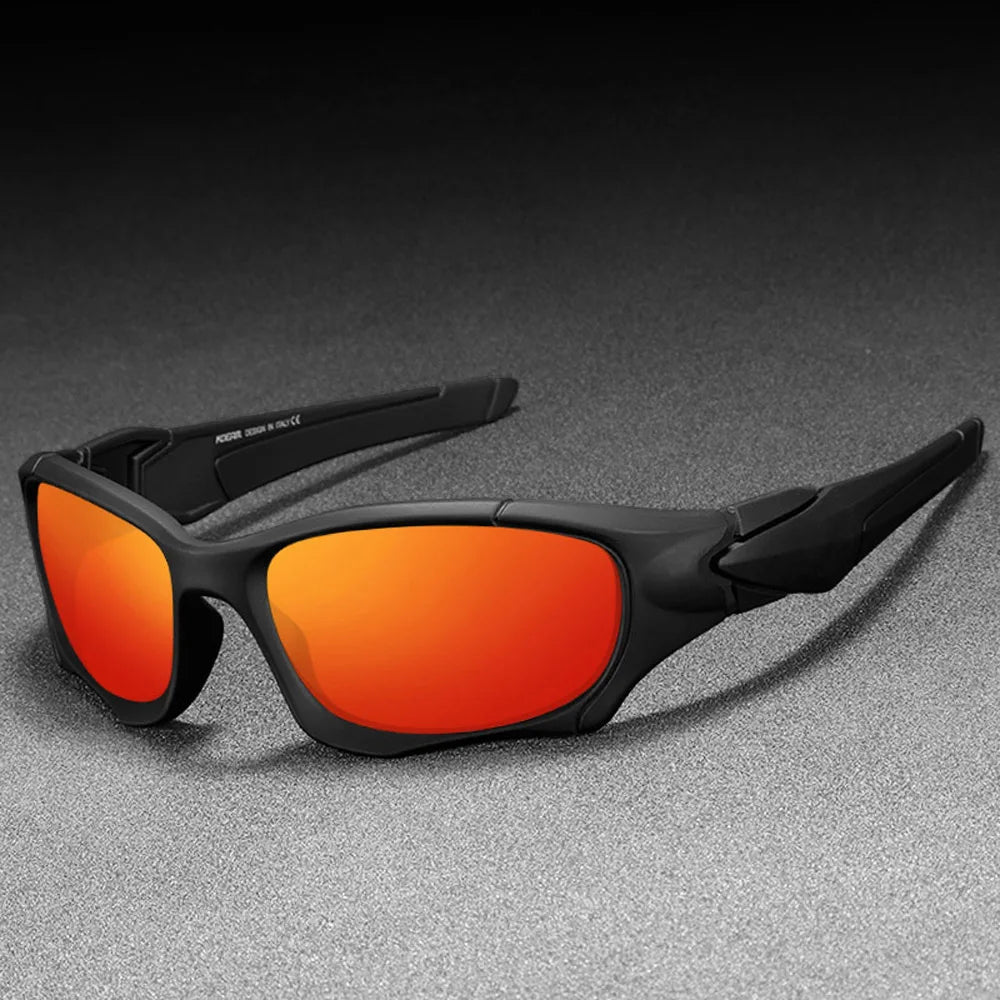 A pair of black sports sunglasses with bright orange lenses resting on a gray surface.