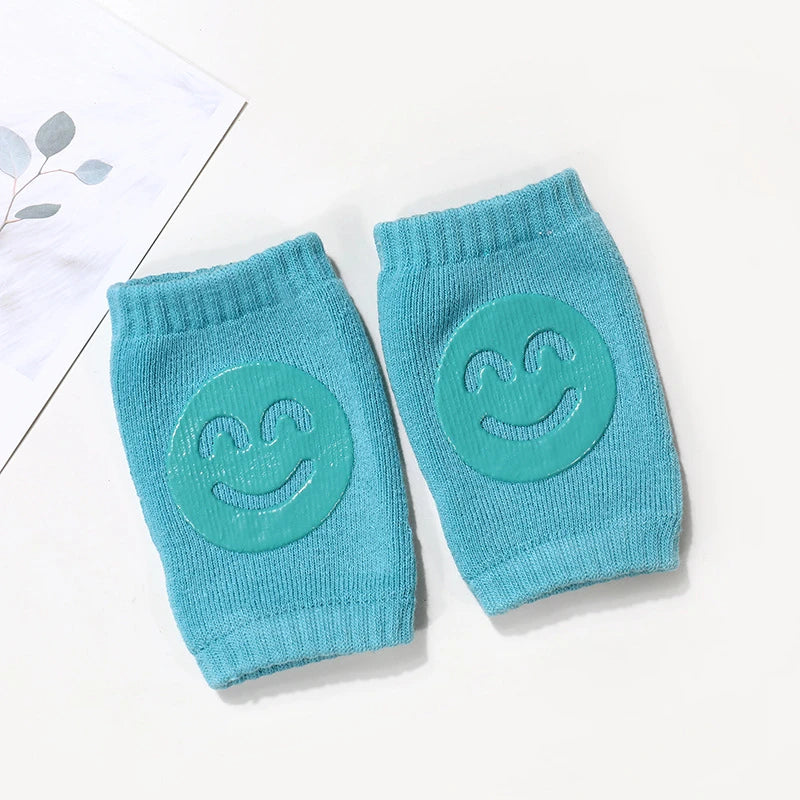 Ein Paar tealfarbener Strick-Wadenwärmer für Baby oder Kleinkind mit lächelndem Gesichtsdruck.