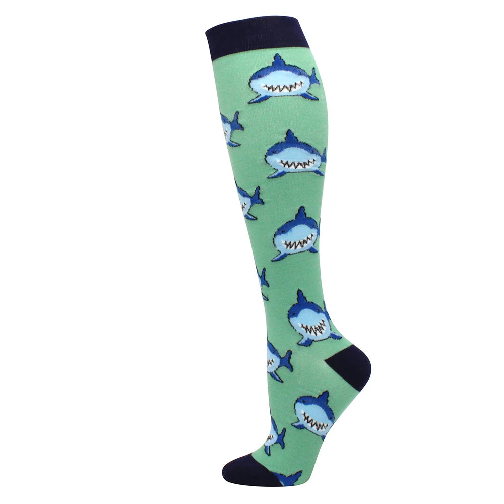 A pair of medical grade compression socks featuring a green background with blue fish designs.