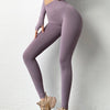 A model wearing mauve high-waist seamless yoga leggings and a matching top, standing against a white wall.