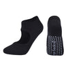 A pair of black breathable women's pilates and yoga socks, one solid and one with white dots.