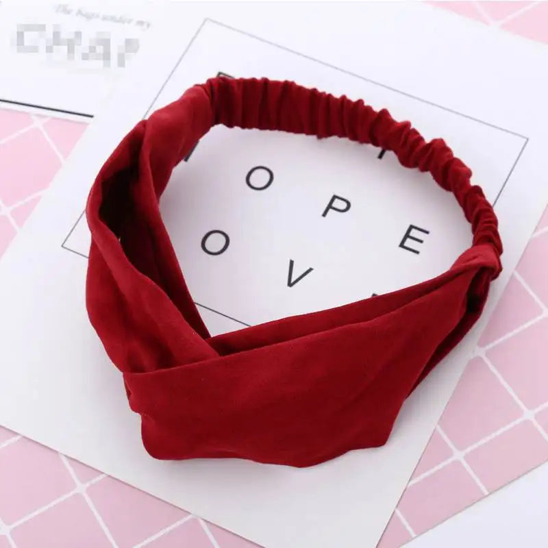 Un bandeau élastique torsadé rouge profond pour bébé fille sur fond blanc.