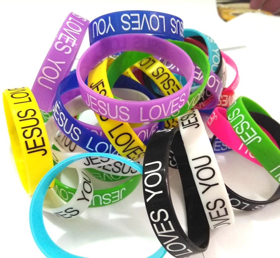 A collection of colorful silicone cuff bracelets with various text designs including Jesus loves you and Jesus loves.