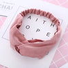 Un bandeau élastique torsadé rose poudré pour bébé fille, sur fond blanc.
