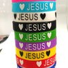 A stack of colorful silicone cuff bracelets with the word JESUS written on each band.