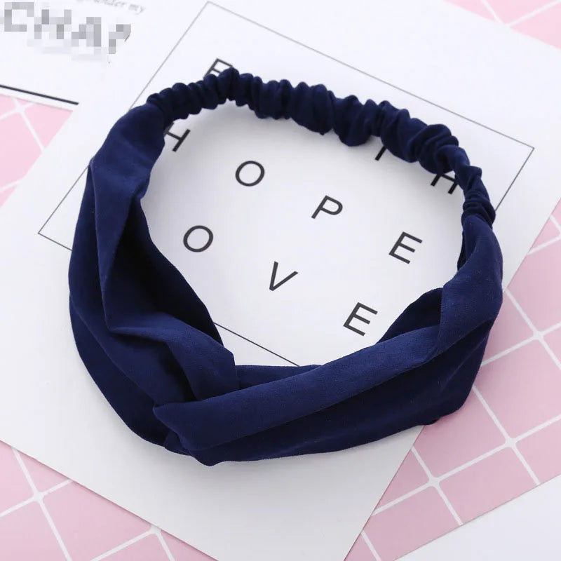 Un bandeau élastique torsadé bleu marine est exposé sur une surface à motifs roses.