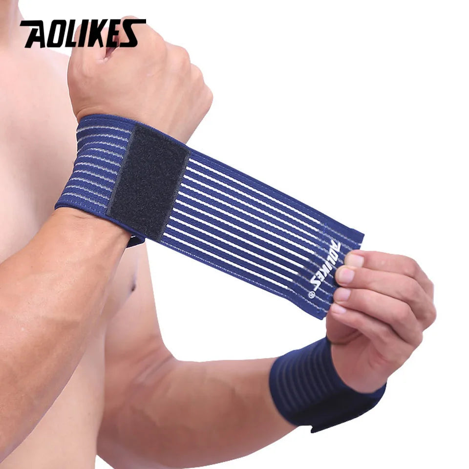 A hand is wearing a dark blue elastic wrist strap with a black pad for sports and daily support.