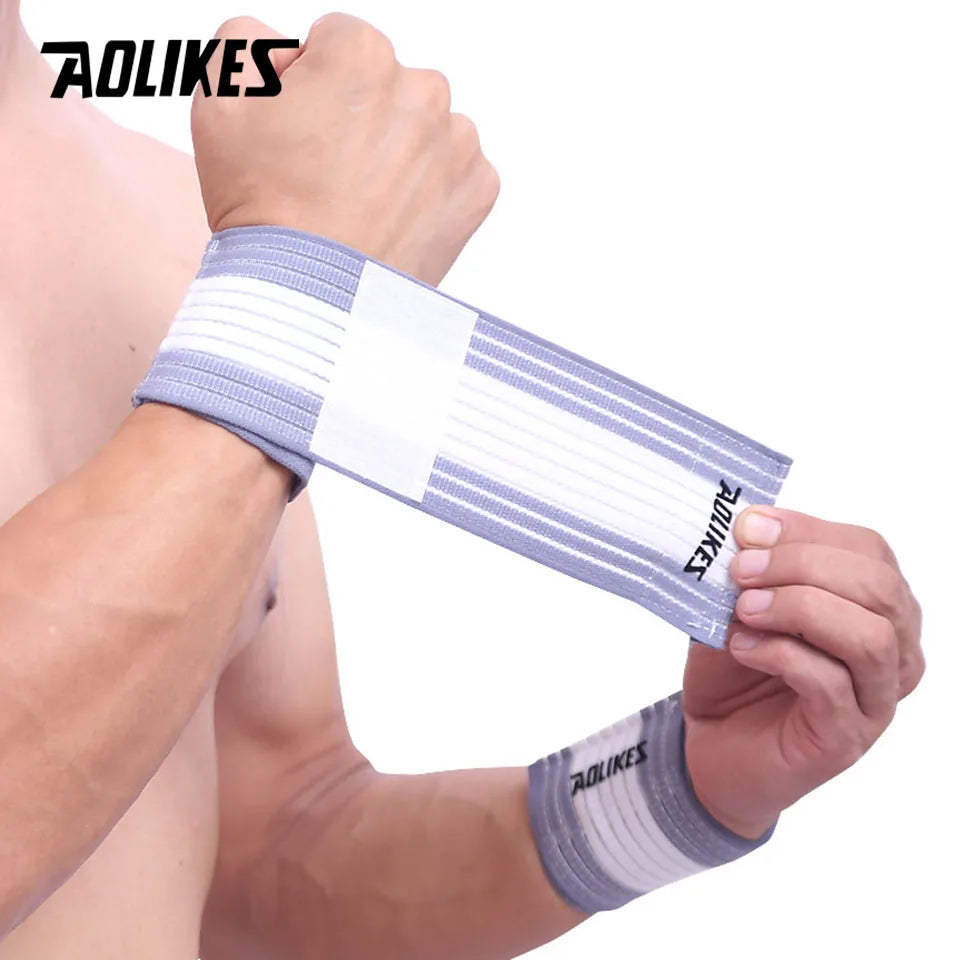 A hand is wearing a white and gray striped elastic wrist strap for sports and daily support.