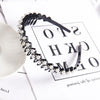 A black headband adorned with small white pearls and rhinestones displayed on a white background.