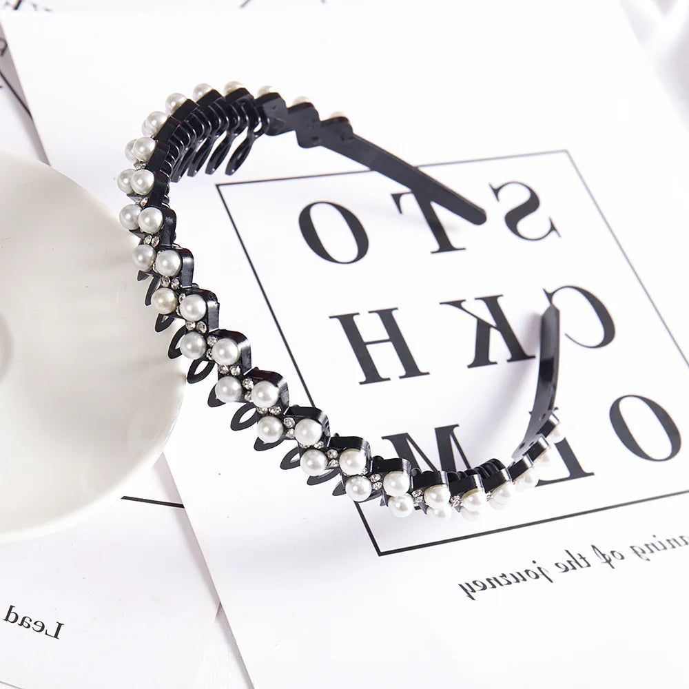 A black headband adorned with small white pearls and rhinestones displayed on a white background.