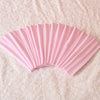 A fan of pink elastic headbands for sports and hair, shown fanned out on a light pink surface.