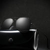 A pair of black polarized pilot sunglasses resting on a black leather case.