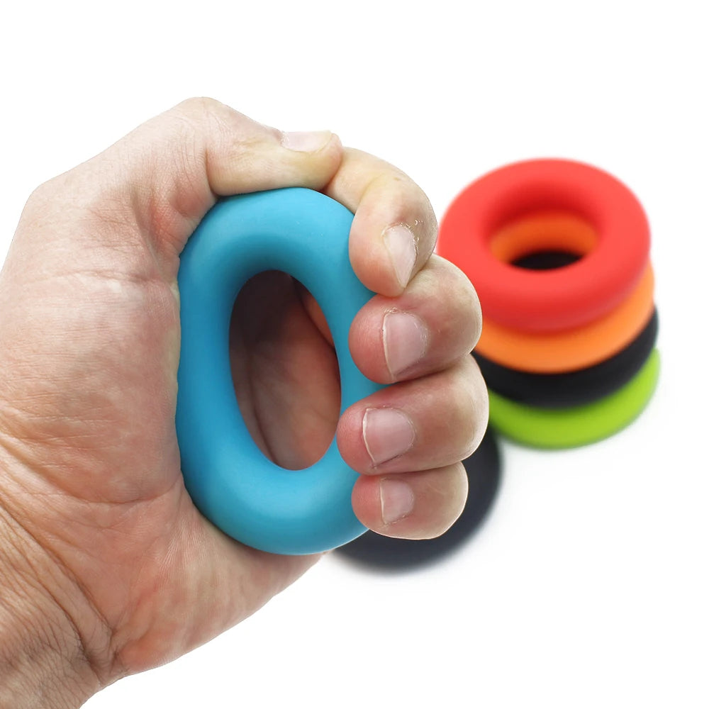 Une main tient un anneau de préhension en silicone bleu, avec une pile d'anneaux colorés en arrière-plan.