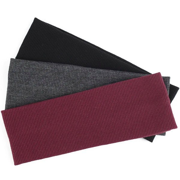 Une pile de trois bandeaux de tête tricotés en coton noir, gris et marron.