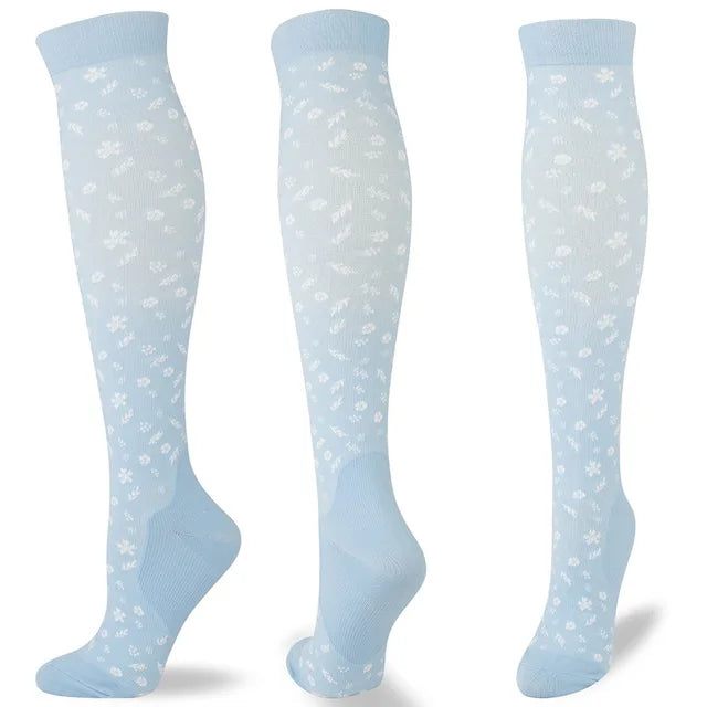 A set of light blue compression socks with a white floral pattern shown in various views.