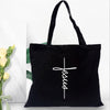 Black canvas tote bag with a white cross design printed on it.