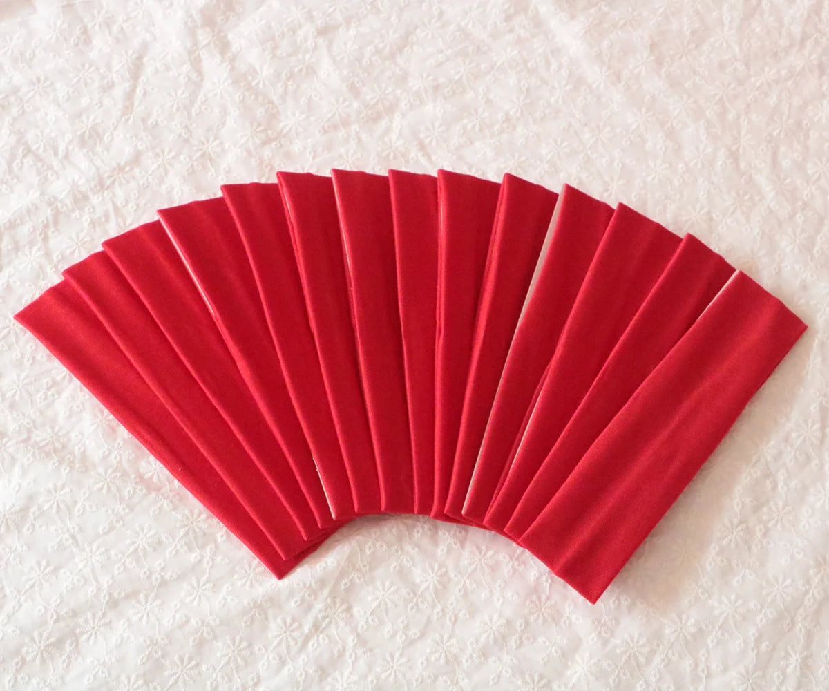 A fan of bright red elastic headbands arranged in a semi-circle on a white surface.