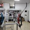 A set of lighted arrow nocks and an archery bow are displayed on a metal rack in a brightly lit room.