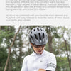 A person wearing a white cycling jersey and black arm sleeves is shown outdoors, possibly riding a bicycle.