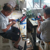A man is assembling or inspecting lighted arrow nocks for archery on a workbench.