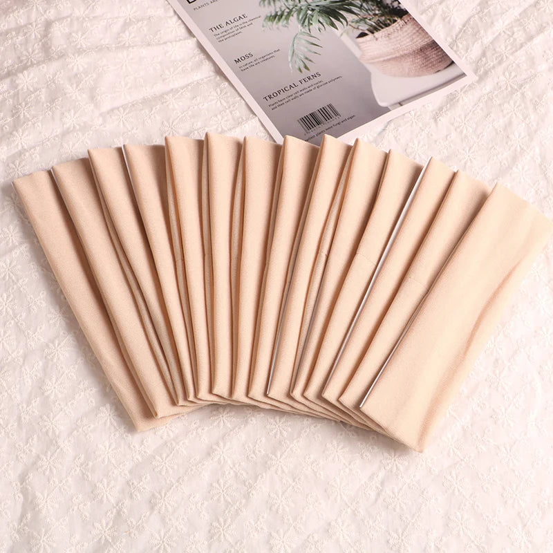 A fan of beige elastic headbands for sports and hair displayed on a white surface next to a product label.