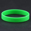 A bright lime green silicone elastic wristband lying on a dark surface.